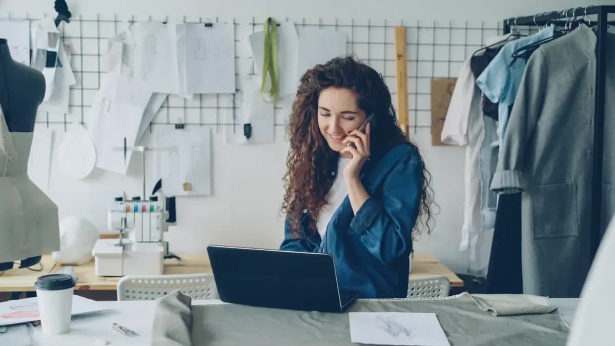 Fashion designer on the phone working on a laptop